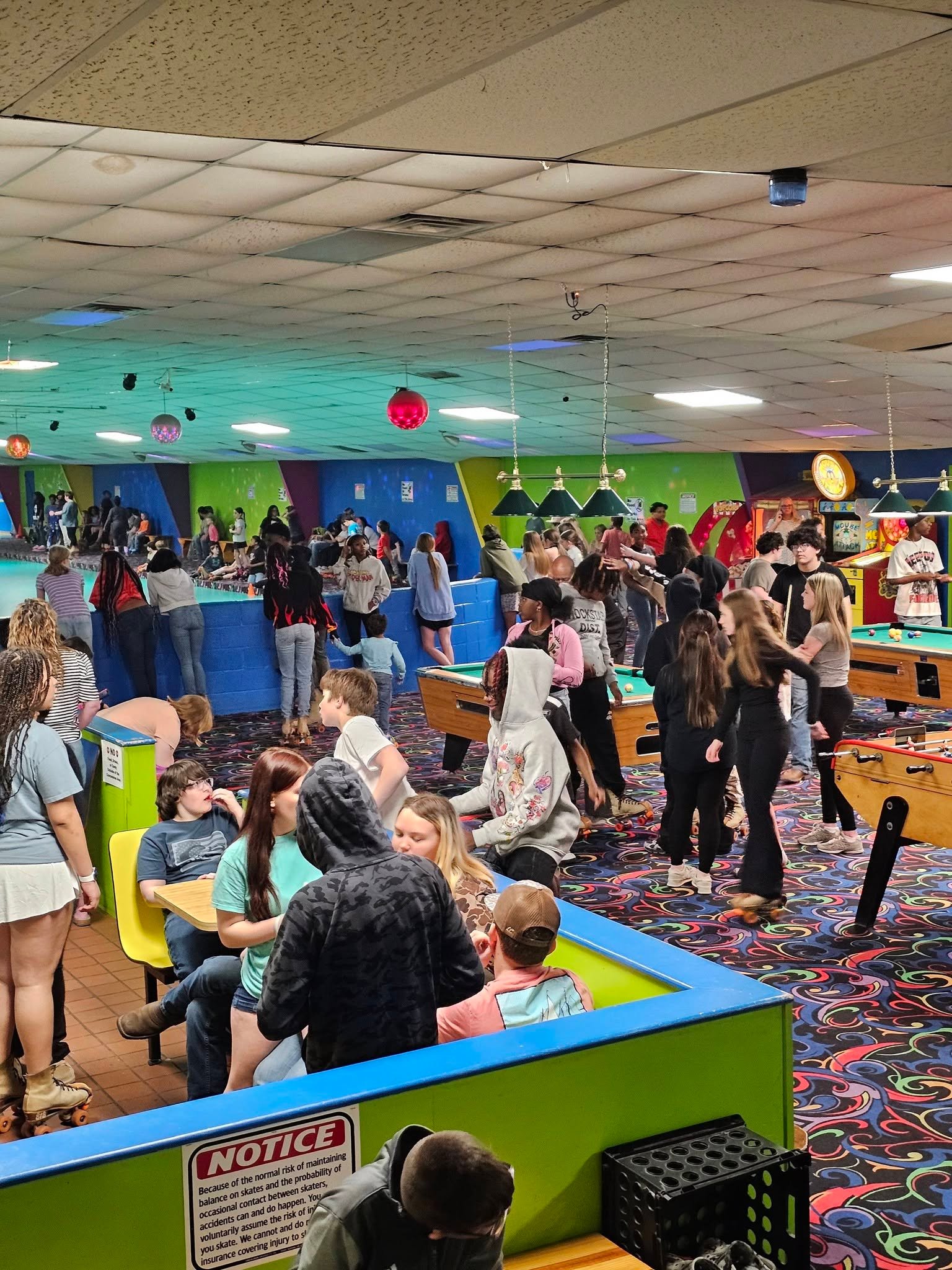 Skaters and guests at the pool tables and rink rail at Hartsville Skating Arena